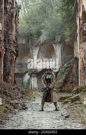 Post-apocalypse nucléaire. Seul survivant en lambeaux et masque à gaz sur les ruines de la ville détruite Banque D'Images