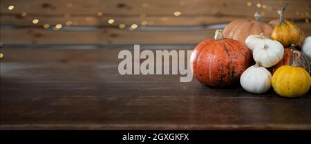 Arrière-plan de fête pour halloween. De nombreuses citrouilles différentes reposent sur une table en bois. Récolte d'automne de graines de citrouille. Baner. Banque D'Images