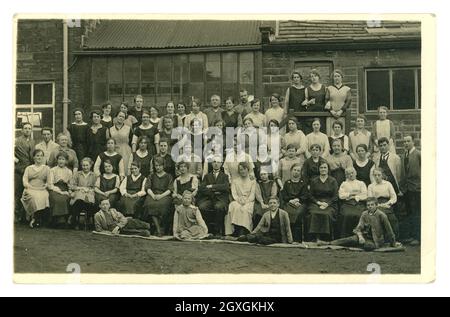 Carte postale originale de l'époque WW1 des ouvriers d'usine, la plupart d'entre eux des femmes. Ils portent des combinaisons très résistantes, leurs superviseurs posent pour la photo du personnel du groupe avec eux. Peut-être ce sont des employés de Listers Mill qui était le plus grand fabricant de soie dans le monde. Emplacement : Girlington, Bradford. West Yorkshire, Angleterre, Royaume-Uni vers 1915, 1916 Banque D'Images