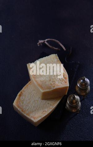 Deux grands morceaux de fromage dur sur fond noir.fromage dur.ensemble d'épices en métal. Vue de dessus. Espace libre Banque D'Images