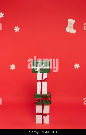 Cadeaux à proximité de flocons de neige décoratifs et bottes sur fond rouge Banque D'Images