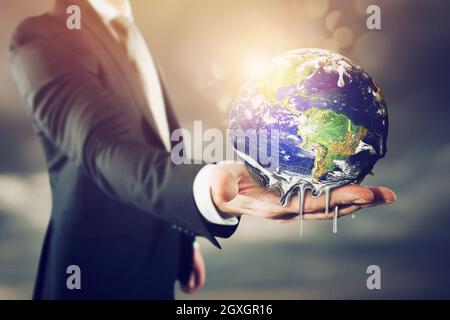 Un homme d’affaires qui tient la terre qui fond . arrête le réchauffement climatique Banque D'Images