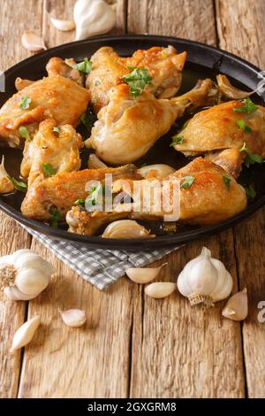 Pollo Al Adillo Classic Spanish Fried Garlic Chicken gros plan sur une assiette sur la table. Verticale Banque D'Images