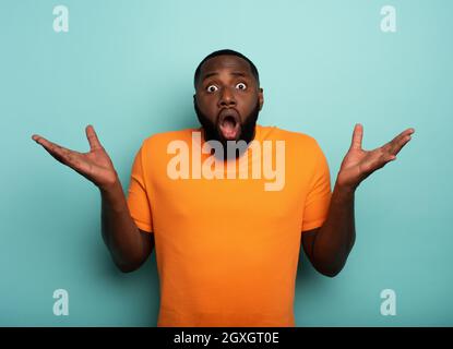 Expression stupéfaite et choquée d'un garçon noir sur le cyan arrière-plan Banque D'Images