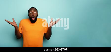 Expression stupéfaite et choquée d'un garçon noir sur le cyan arrière-plan Banque D'Images