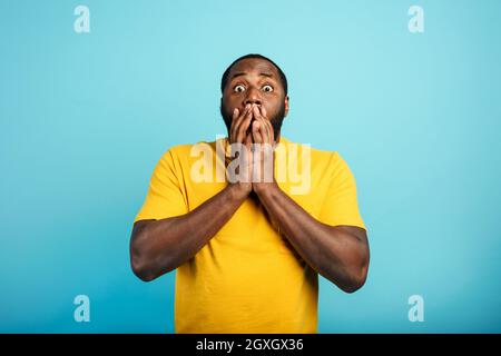 Expression stupéfaite et choquée d'un garçon noir sur le cyan arrière-plan Banque D'Images