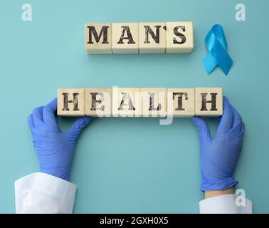 cubes en bois avec l'inscription santé de l'homme et deux mains d'un médecin en gants bleus. Concept pour le diagnostic opportun du cancer de la prostate chez les hommes, healt Banque D'Images