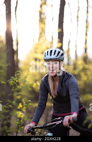 Jolie, jeune femme avec son vélo tout-terrain allant pour un tour au-delà des limites de la ville, obtenant sa dose de cardio quotidienne Banque D'Images