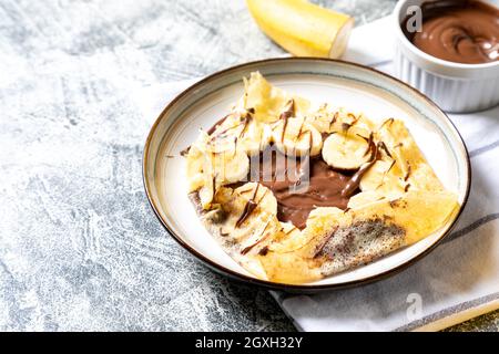 Crêpes, crêpes fines sur une assiette. Tartinade au chocolat et crêpes fourrées à la banane sur l'assiette. Crêpes savoureuses ou blini à la sauce sucrée. Banque D'Images