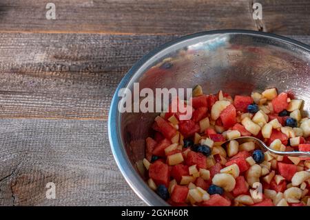 Fruits frais hachés et marinés dans un bol isolé sur une table en bois Banque D'Images