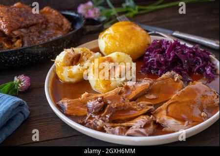 Faites rôtir la dinde avec de la sauce, des boulettes de pommes de terre et du chou rouge.Dîner traditionnel le dimanche ou le jour férié.Servi sur une assiette sur une table rustique en bois. Banque D'Images