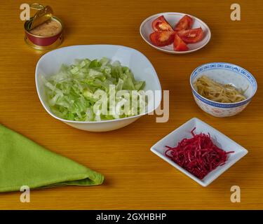 Ingrédients pour préparer une salade de thon et de légumes verts décorée d'une serviette sur fond de bois. Banque D'Images