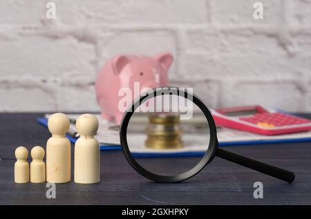 figurines de famille en bois et banc de porc en céramique rose sur fond bleu. Concept de l'accumulation d'espèces pour l'achat d'une maison et d'une voiture, de l'argent dans la banque Banque D'Images