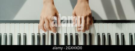 Femme apprenant à jouer du piano à la maison sur clavier numérique. Bannière panoramique crop de mains jouant des accords débutants pour apprendre à jouer par elle-même Banque D'Images