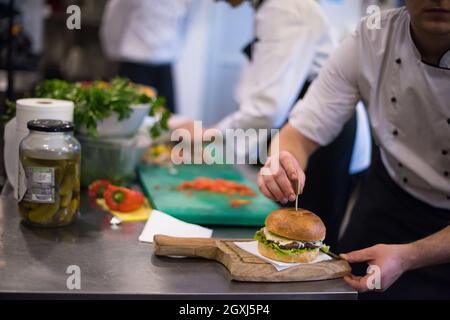 Master chef putting cure-dents sur un hamburger dans une cuisine de restaurant Banque D'Images