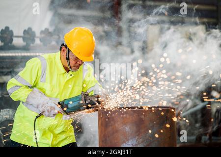 Un travailleur asiatique travaille en usine sur le meulage de roues électriques sur une structure en acier. Banque D'Images