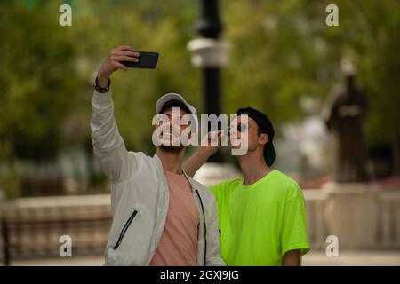 Deux beaux amis masculins traînent et prennent des selfies ensemble Banque D'Images