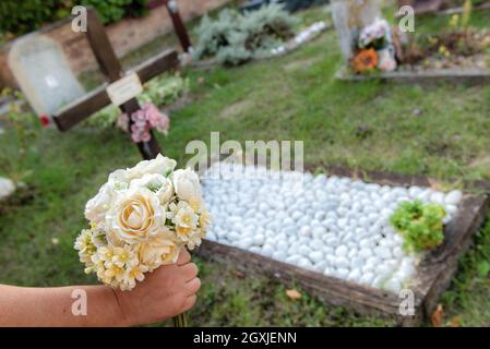 Femme apporte des fleurs au cimetière à l'occasion de la fête de commémoration des morts, ou jour des morts Banque D'Images