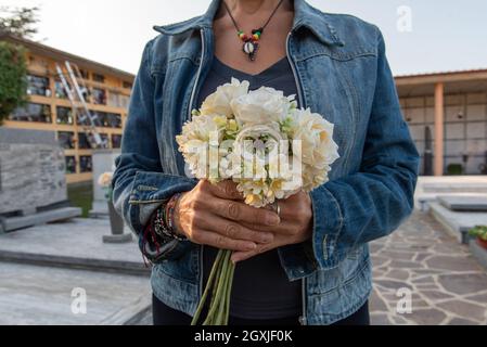 Femme apporte des fleurs au cimetière à l'occasion de la fête de commémoration des morts, ou jour des morts Banque D'Images