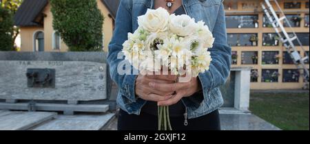 Femme apporte des fleurs au cimetière à l'occasion de la fête de commémoration des morts, ou jour des morts Banque D'Images