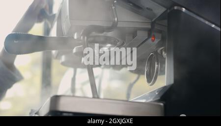 Main du barista nettoyant la vapeur et la fumée réchauffez le lait de la machine à café, vaporiseur par pression de diffusion, faire couler de l'eau dans une tasse de café Banque D'Images