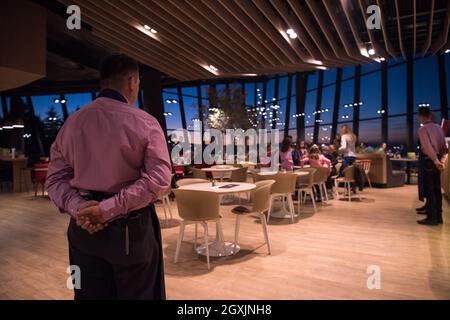 Vue arrière du jeune garçon confiant debout avec les mains derrière le dos dans un restaurant de luxe Banque D'Images