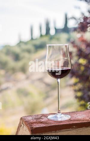 Bénéficiant d''un verre de vin rouge à la Toscane, Italie. Vignobles flou en arrière-plan. Banque D'Images