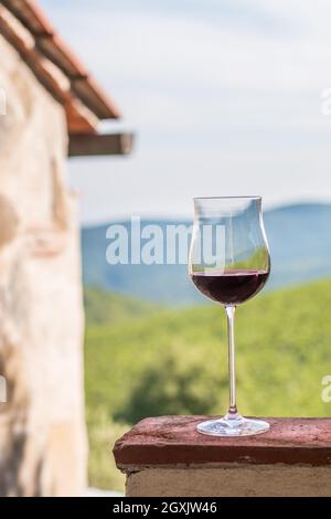 Bénéficiant d''un verre de vin rouge à la Toscane, Italie. Vignobles flou en arrière-plan. Banque D'Images