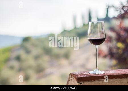 Bénéficiant d''un verre de vin rouge à la Toscane, Italie. Vignobles flou en arrière-plan. Banque D'Images