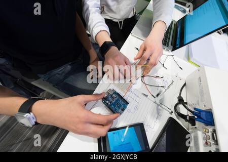 Il classe les étudiants en informatique qui travaillent ensemble sur le projet avec un mini-pc hardware et logiciel de programmation de code sur l'ordinateur portable Banque D'Images