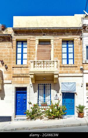 Architecture résidentielle maltaise typique avec portes d'entrée en bois aux couleurs vives, fenêtres à persiennes et balcons en bois fermés - Tarxien, Malte. Banque D'Images