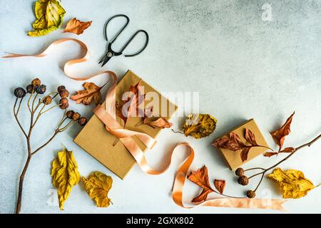 Boîte cadeau automnale attachée avec un ruban et des décorations de feuilles d'automne séchées sur une table Banque D'Images