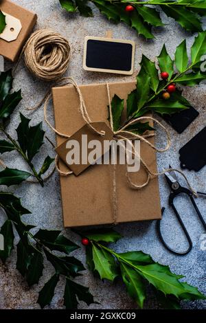 Boîte cadeau emballée décorée de houx frais pour Noël Banque D'Images