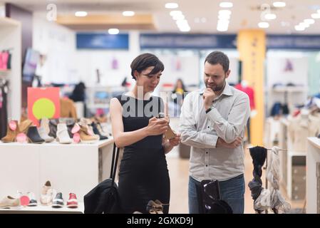 Un jeune beau couple change le regard avec de nouvelles chaussures Magasin de chaussures à Banque D'Images