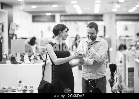 Un jeune beau couple change le regard avec de nouvelles chaussures Magasin de chaussures à Banque D'Images