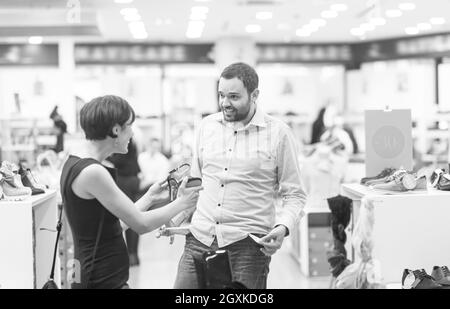 Un jeune beau couple change le regard avec de nouvelles chaussures Magasin de chaussures à Banque D'Images