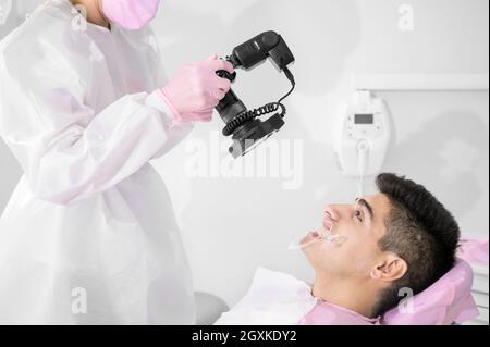 Dentiste avec appareil photo pour prendre des photos du sourire d'un jeune patient. Photo de haute qualité. Banque D'Images
