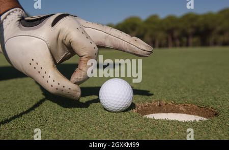 Close up of man's hand putting balle de golf dans le trou en cours Banque D'Images