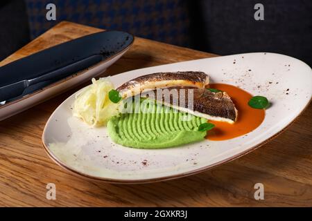 Cuisine fine filets de Seabass sur purée de pommes de terre de carottes et épices sur la table, servant dans un restaurant, concept de menu. Banque D'Images