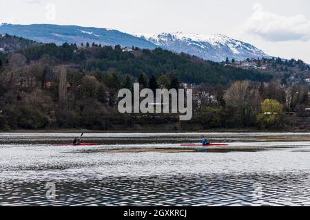 Les gens kayak au loin sur un lac en Bulgarie. Sombre nuageux jour sombre en hiver.Snowy montagnes au loin. Banque D'Images