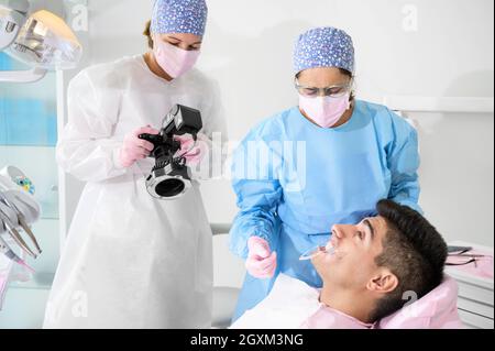 Dentiste avec appareil photo pour prendre des photos du sourire d'un jeune patient. Photo de haute qualité. Banque D'Images