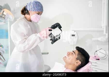Dentiste avec appareil photo pour prendre des photos du sourire d'un jeune patient. Photo de haute qualité. Banque D'Images