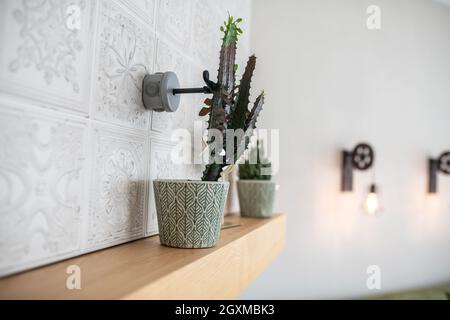 Magnifique maison dans les pots à fleurs à motifs sur une mantelclayette en bois Banque D'Images