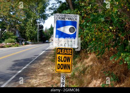 Un panneau de surveillance de la criminalité dans le quartier et un panneau de ralentissement sur un poteau monté en bord de route. Banque D'Images