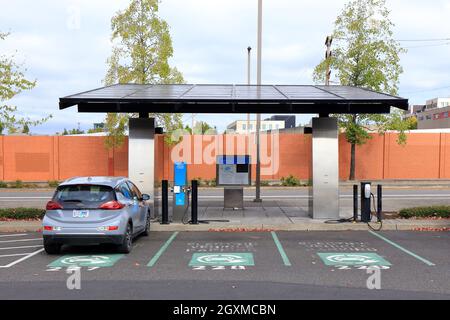 Un poste de charge de véhicule électrique à toit solaire avec casiers de charge de batterie ebike au parking de l'ODSI à Portland, Oregon Banque D'Images