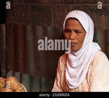 Un vendeur malvoyants femme âgée portant un hijab musulman vendant des légumes dans un marché humide à Bukittinggi, Sumatra Ouest, Indonésie. Banque D'Images