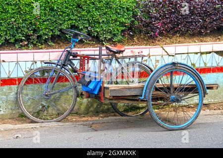 Tricycle de style ancien stationné sur le côté d'une route servant au transport de marchandises dans la ville de Bukittinggi, Sumatra Ouest, Indonésie. Banque D'Images