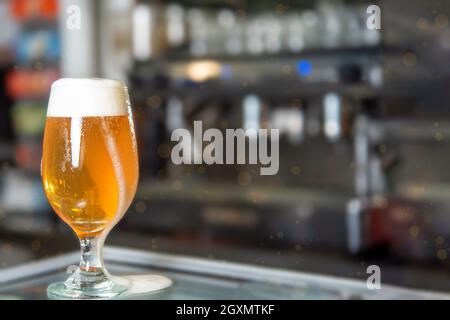 Verre de bière sur le comptoir du bar, frais, magnifiquement coloré avec la mousse tombant à travers le verre Banque D'Images