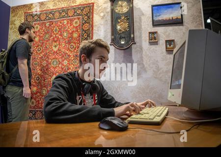 Moscou, Russie.3 octobre 2019 Un jeune homme joue à des jeux sur un ordinateur des années 1990 dans un intérieur de maison de l'ère soviétique au Comic con Russia 2019 et aux expositions de jeux informatiques et vidéo d'Igromir 2019 au Centre d'exposition international Crocus Expo dans la région de Moscou, Russie Banque D'Images