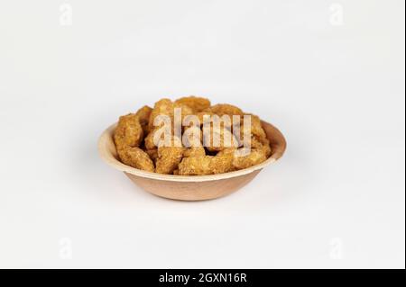 Croustilles de banane enrobées de jaggery ou sharkara varatti dans une areca bol à feuilles sur fond blanc Banque D'Images